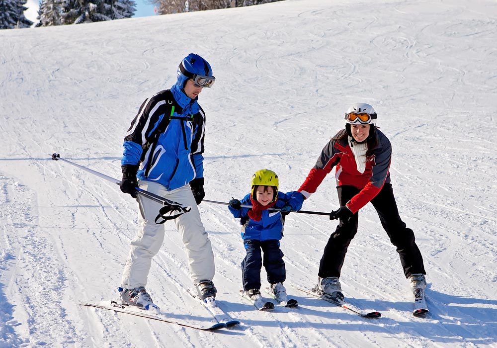 Parents with child downhill skiing on a groomed trail