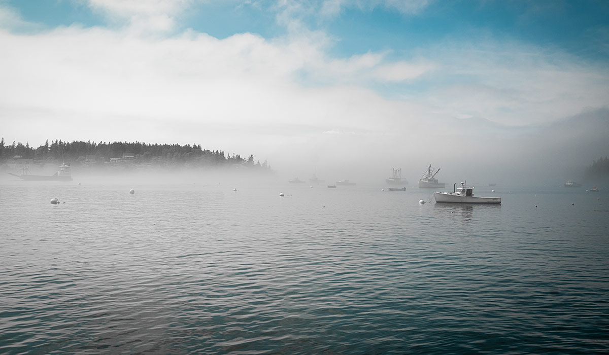 Foggy view of the ocean, boats, and Monhegan Island, Maine from the ferry.