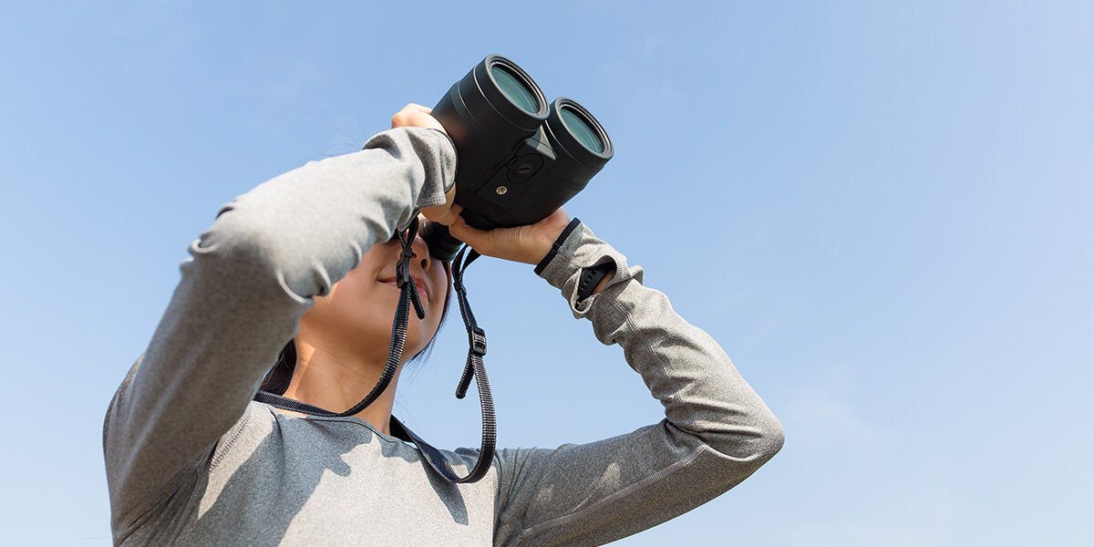 Young woman birdwatching with binoculars