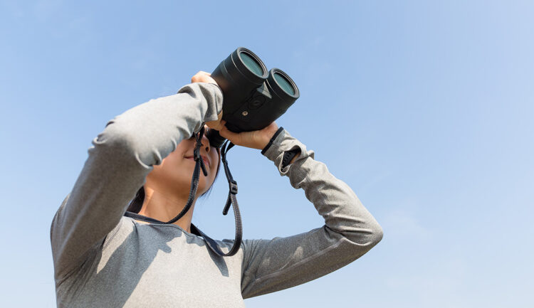 Young woman birdwatching with binoculars